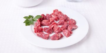 Cut up pieces of raw meat on a plate