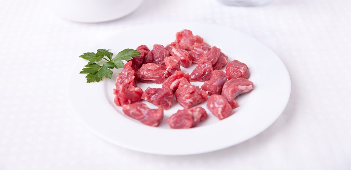 Cut up pieces of raw meat on a plate